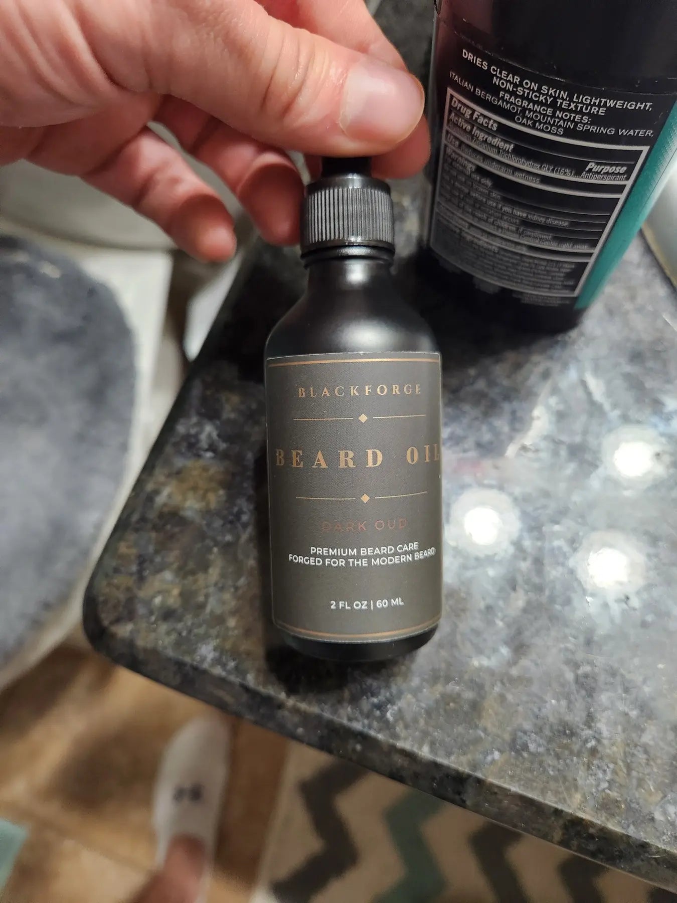 Dark Oud BlackForge beard oil bottle photographed beside grooming products